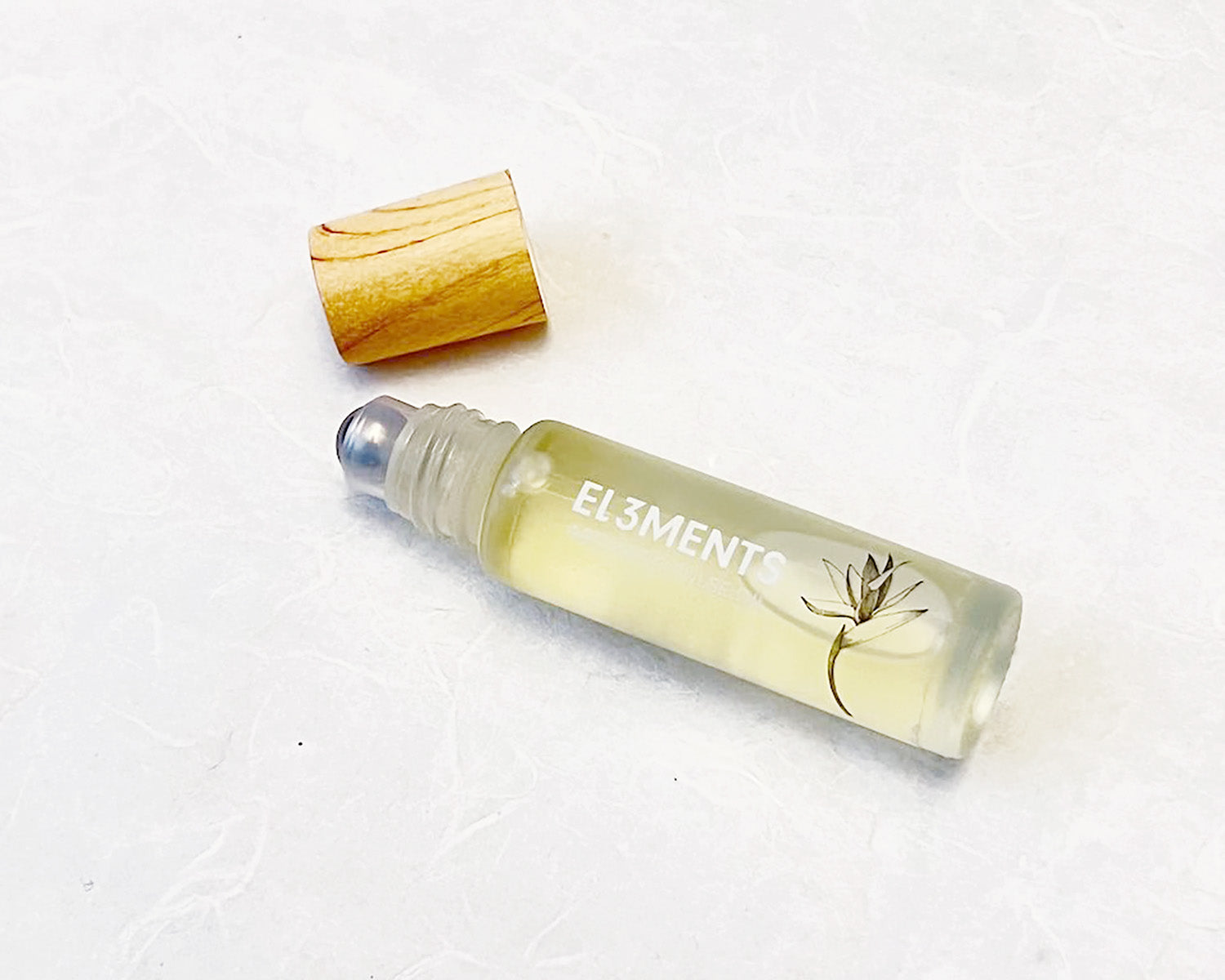 Roll-on fragrance oil bottle labeled EL3MENTS with bamboo cap on a white background