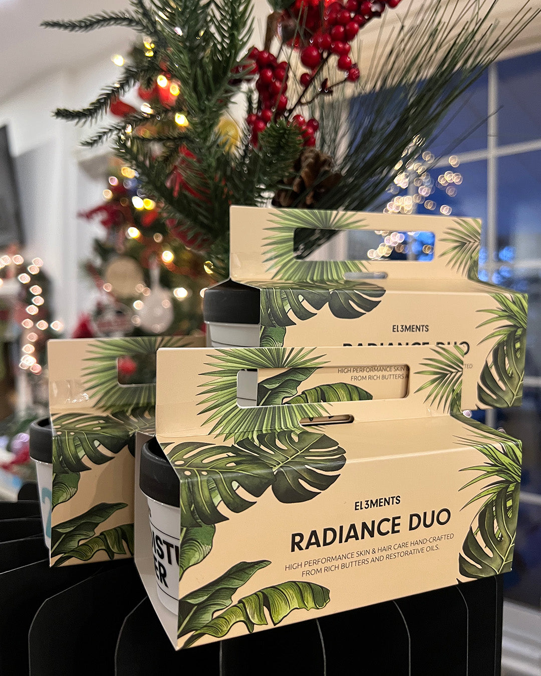 Cosmetic Radiance Duo packaging with leaf design in front of a decorated Christmas tree