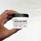 Hand holding MOISTURE-RISER Body Butter demi jar on white background