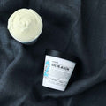 Salve-ation Body Butter jars open showing texture on grey linen background