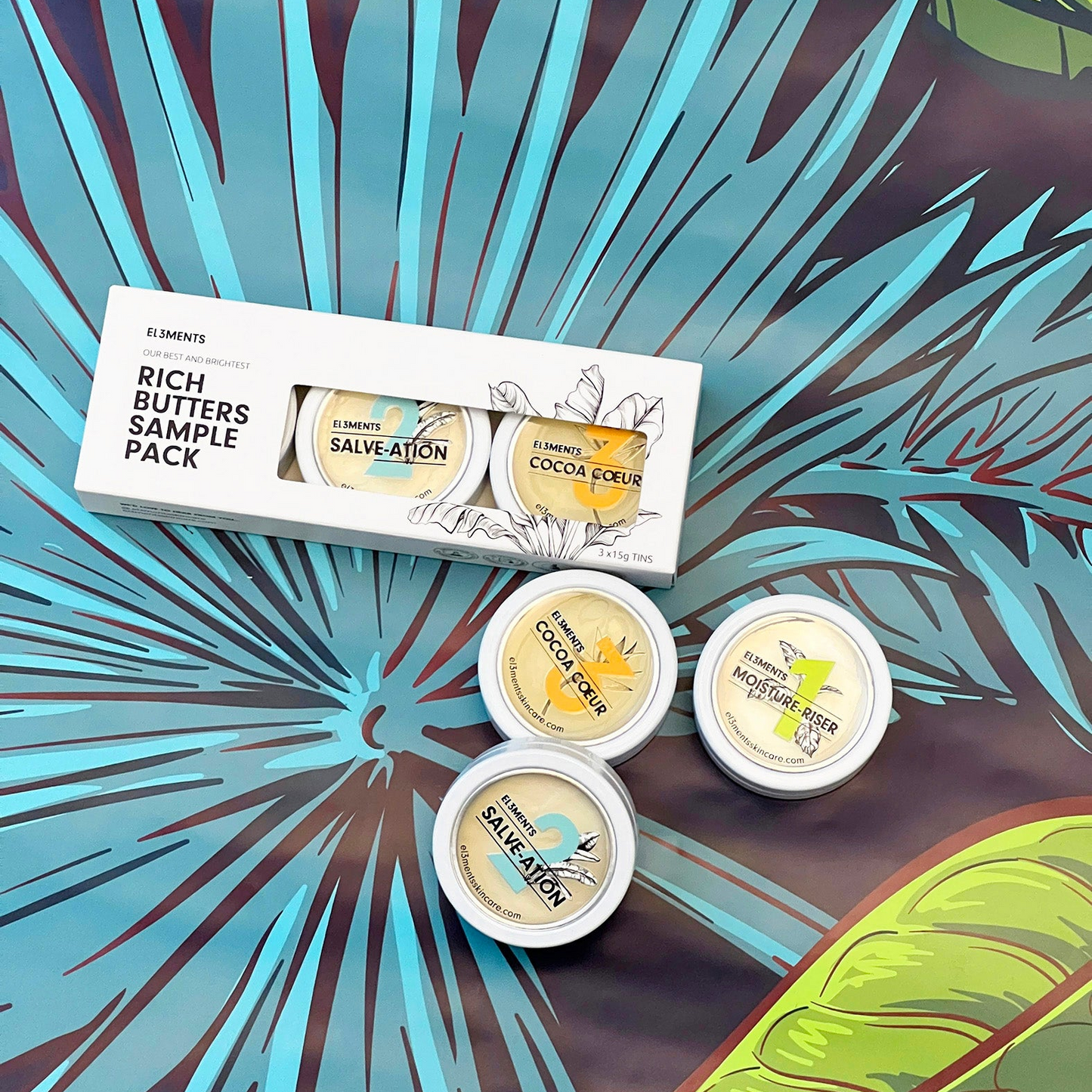 El3ments Rich Butters Sample Pack with additional aluminum tins  on a tropical background