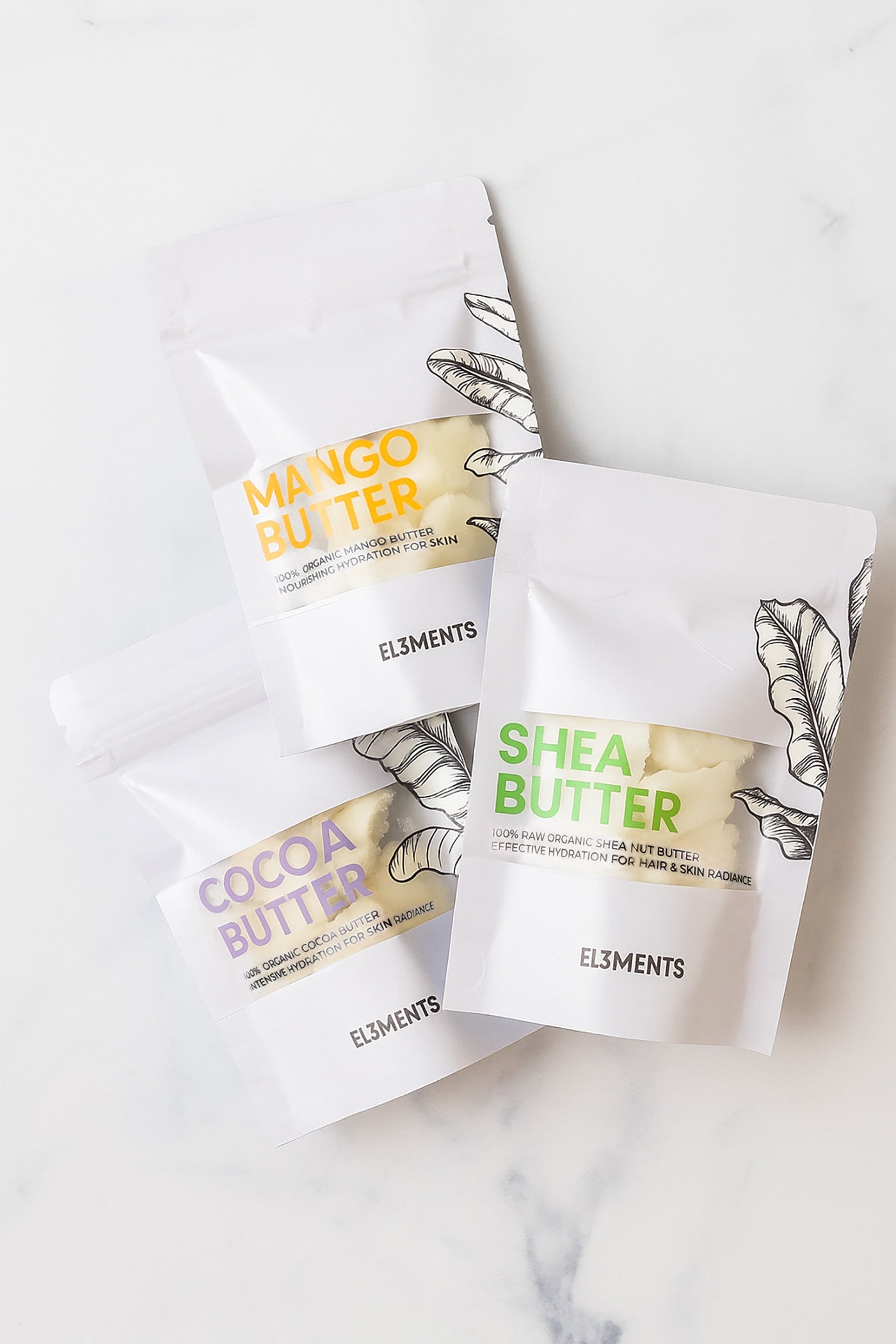 Shea butter, mango butter, cocoa butter packages on a white marble surface