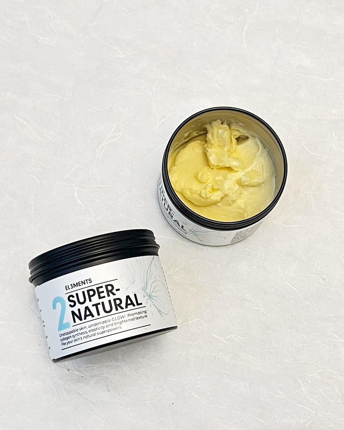 Two containers of Super-Natural body butter stretch mark product on a textured white background